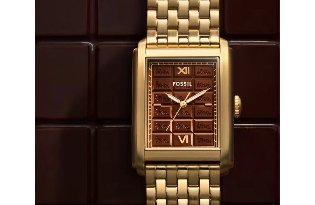 A gold watch with brown face sitting on top of a wall.