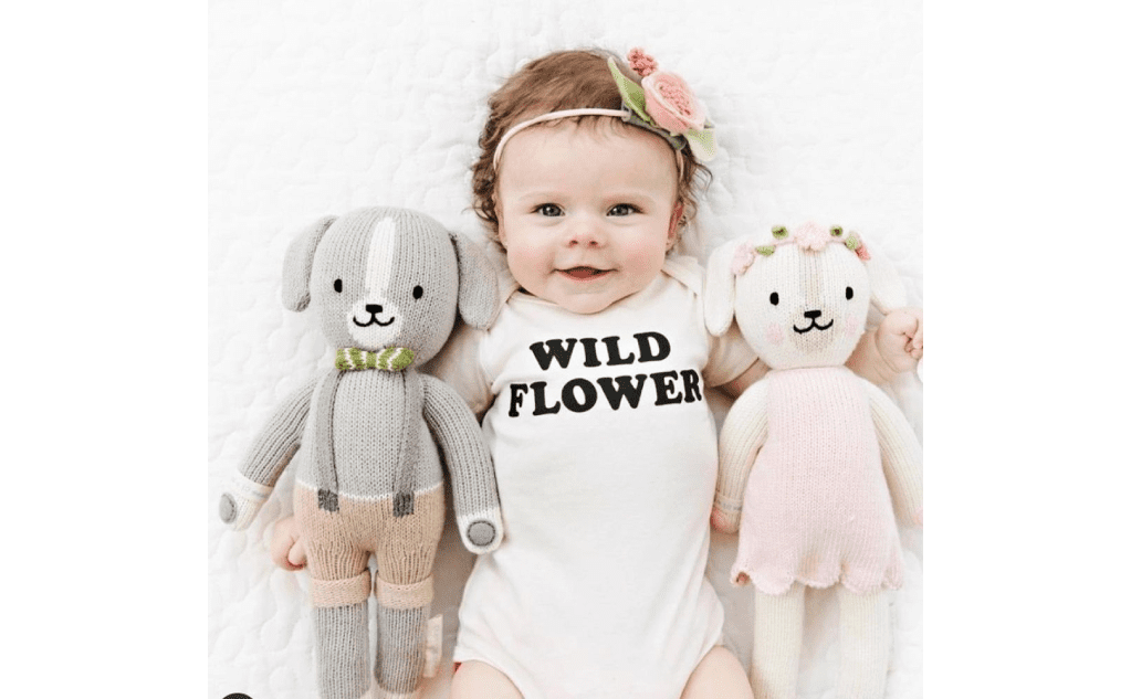 A baby girl with two stuffed animals and a headband.