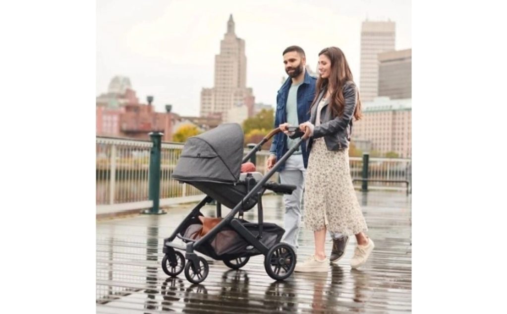A man and woman pushing a stroller in the rain.