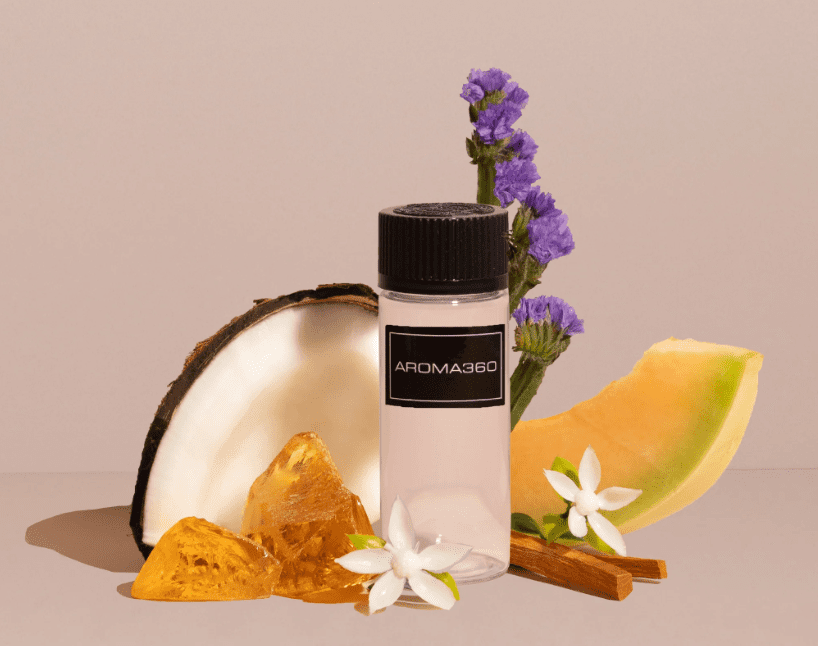 A bottle of perfume next to some flowers and coconut.