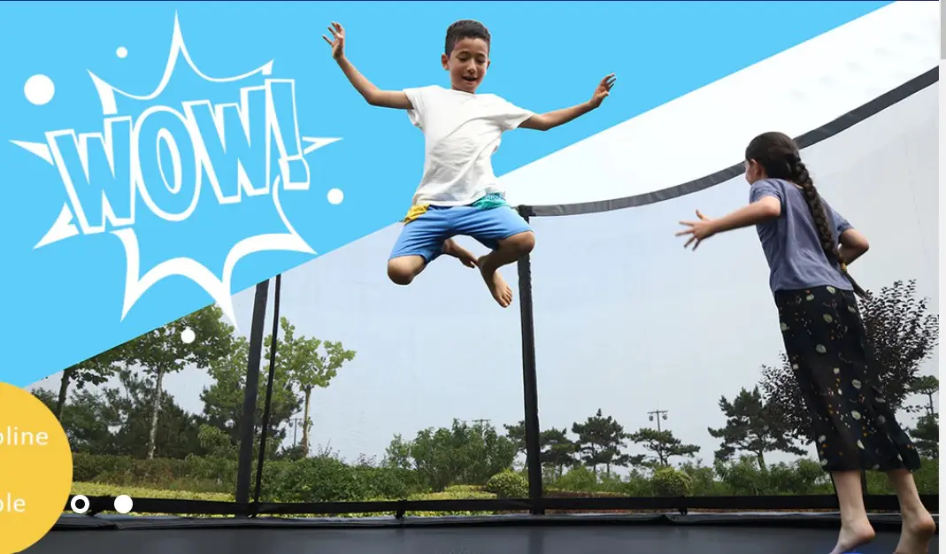 A boy jumping on the trampoline with his arms raised.