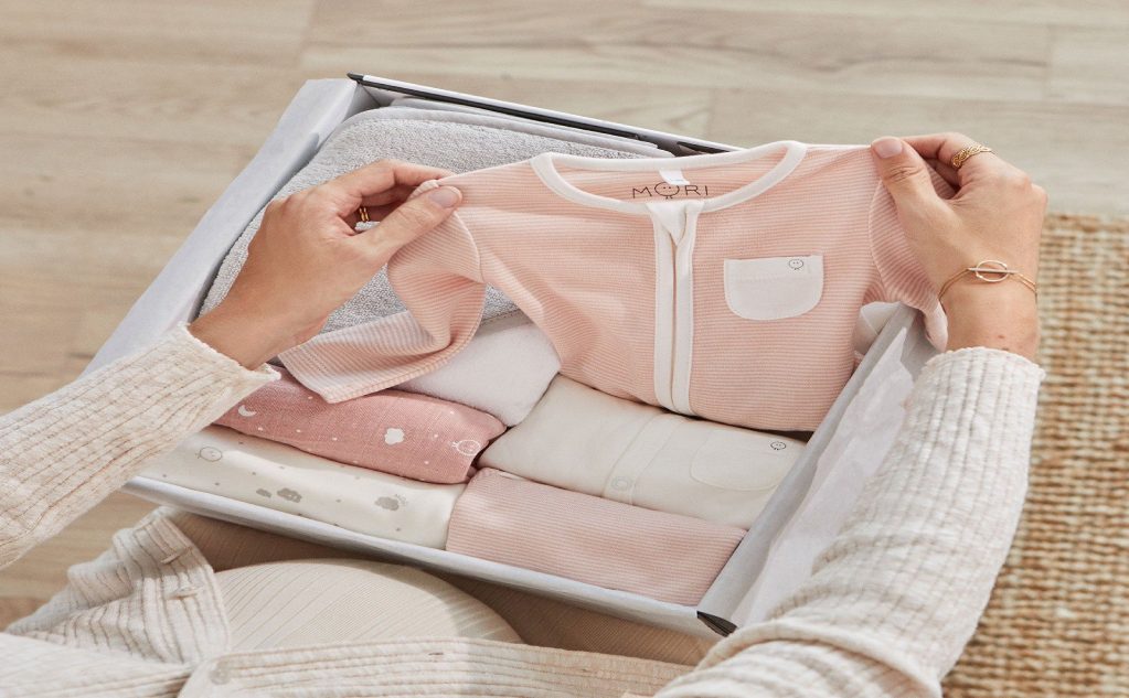 A person is folding clothes in an open box.
